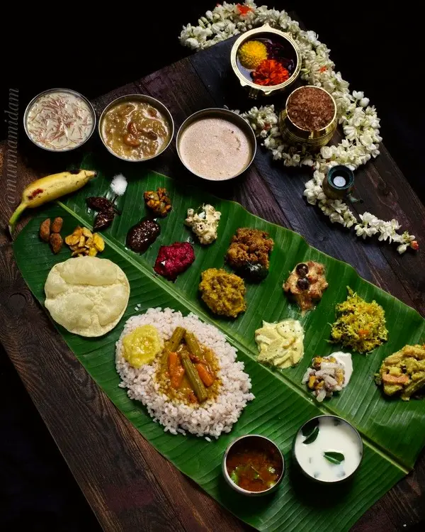 Festive banana-leaf feast with rice, curries, appalam and jasmine on a wooden table