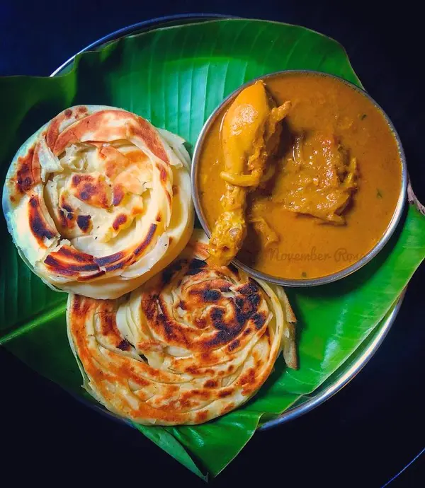 Flaky parottas with chicken curry on a banana leaf