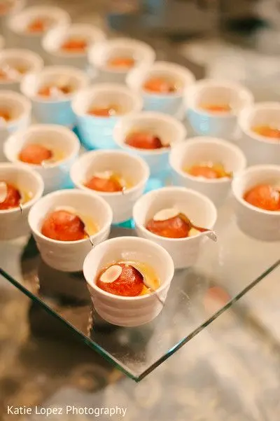 Gulab jamun served in small cups on a glass tray